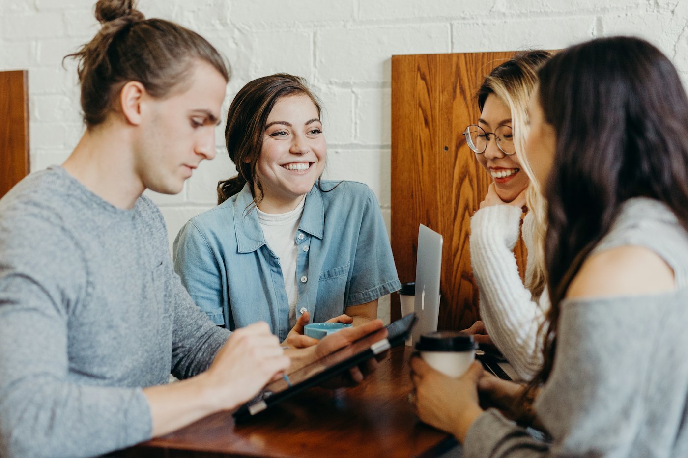 Four colleagues working together and laughing at a café table